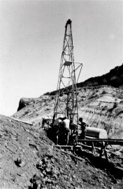 A drilling rig at Four Aces Claim in August 1955 with the sloping Chinle shale mostly hiding the tall Wingate cliffs of Copper Point. (Most crews had one driller often in his 20s and two teenage kids. The latter often liked to shoot at the common, tiny (6 to 10 inches long and under 1/2 inch diameter) sidewinders. Since we all wore boots this shooting was much more dangerous (bullets fly off rocks in surprising directions) than the snakes themselves. They are only dangerous when you sleep on the ground. They may slide into your sleeping bag to escape the cold desert nights and if you role over a bite in the wrong place could easily be fatal.